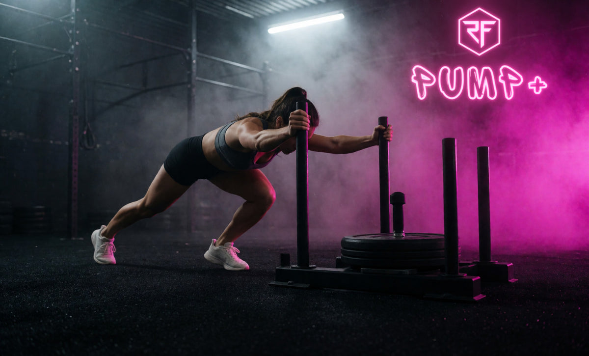 An athlete driving a heavy sled push through pink-lit haze in a dark gym